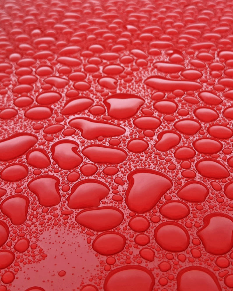 Gotas de água sobre o teto vermelho e brilhante de um carro polido